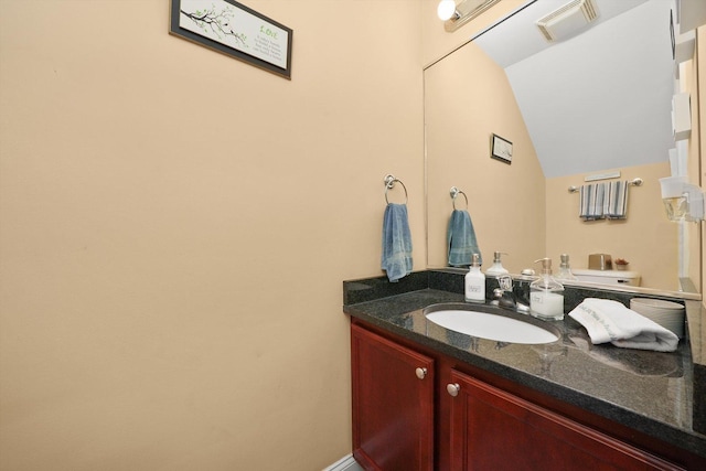 bathroom featuring visible vents, lofted ceiling, and vanity