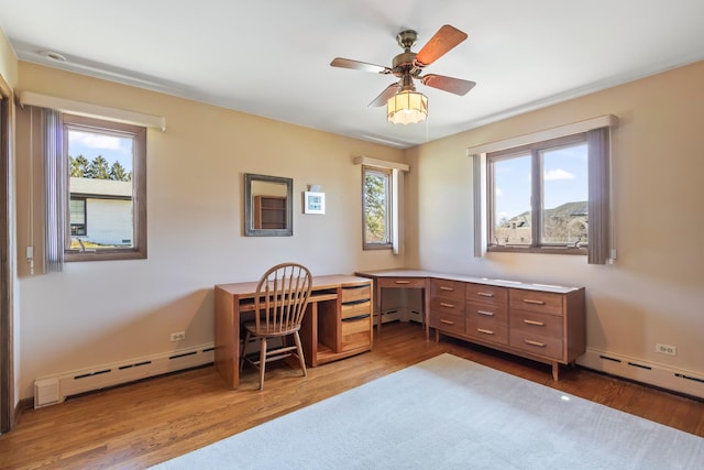 office space with wood finished floors, a baseboard heating unit, and a wealth of natural light