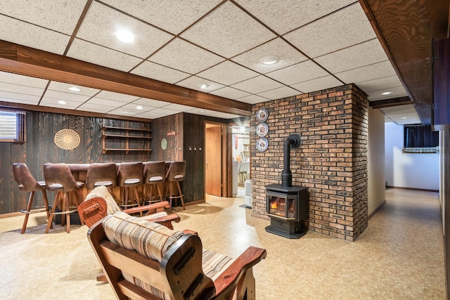living room with a paneled ceiling, a wood stove, a dry bar, recessed lighting, and wood walls