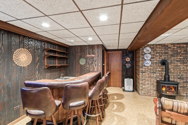 bar with bar area, a wood stove, wood walls, and carpet floors