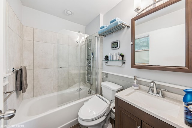 bathroom with toilet, vanity, and bath / shower combo with glass door