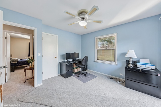 carpeted home office with ceiling fan and baseboards