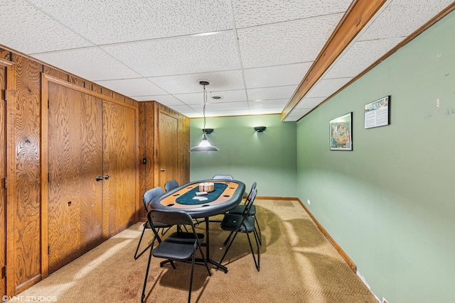 dining space with baseboards, a drop ceiling, and light colored carpet