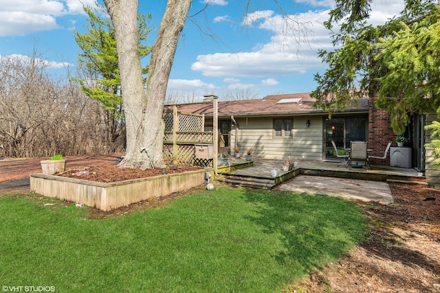 back of property with a deck and a lawn