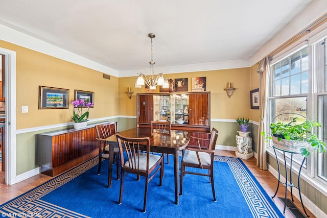 dining room featuring baseboards, wood finished floors, a notable chandelier, and visible vents