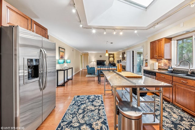 kitchen with tasteful backsplash, light wood-style flooring, crown molding, brown cabinetry, and appliances with stainless steel finishes