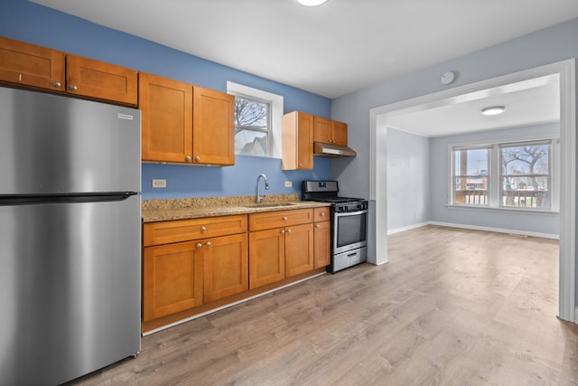 kitchen with light stone counters, a sink, plenty of natural light, and stainless steel appliances