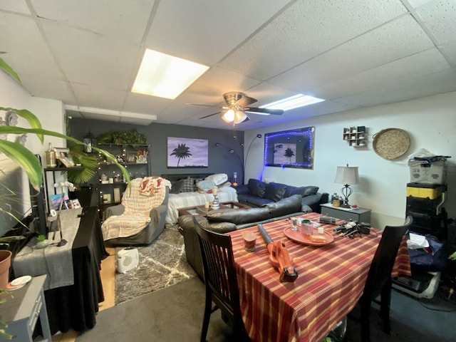dining room with concrete floors, ceiling fan, and a drop ceiling
