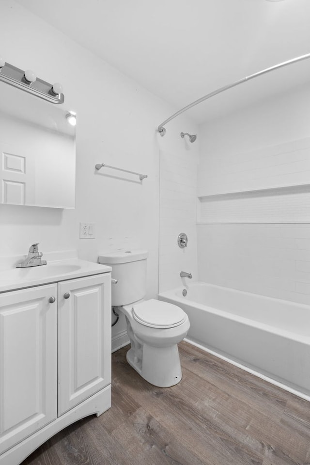 bathroom featuring toilet, wood finished floors, vanity, and shower / bathtub combination