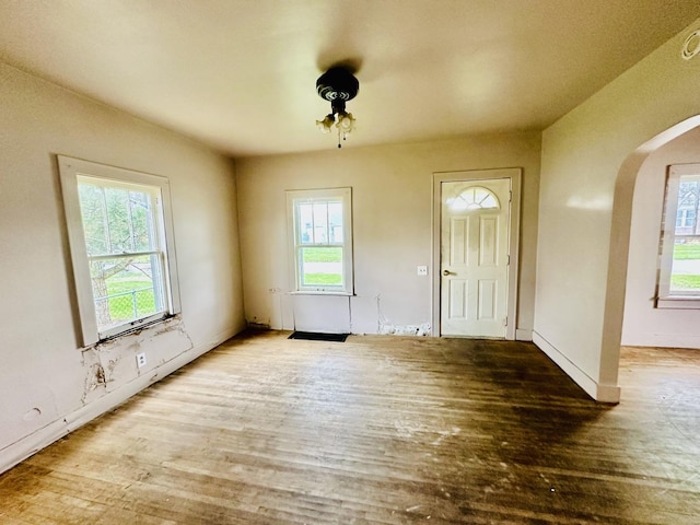 entrance foyer featuring arched walkways, wood finished floors, and baseboards