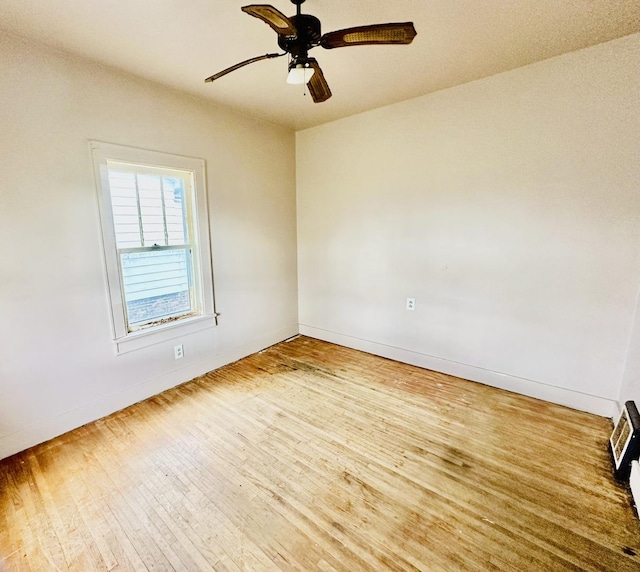 spare room with wood finished floors, baseboards, a ceiling fan, and visible vents