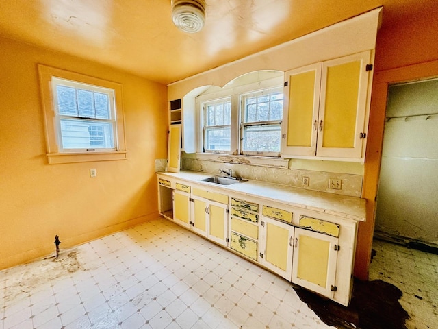 kitchen featuring light countertops, a sink, plenty of natural light, and light floors
