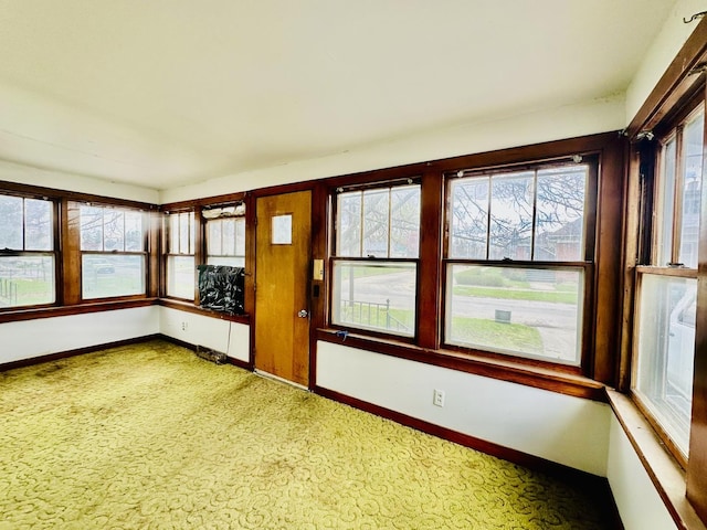 unfurnished sunroom with carpet flooring and baseboards