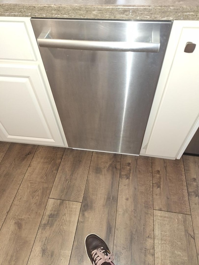 room details with white cabinetry, wood finished floors, and dishwasher