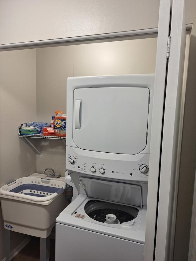 washroom with a sink, stacked washer / dryer, and laundry area
