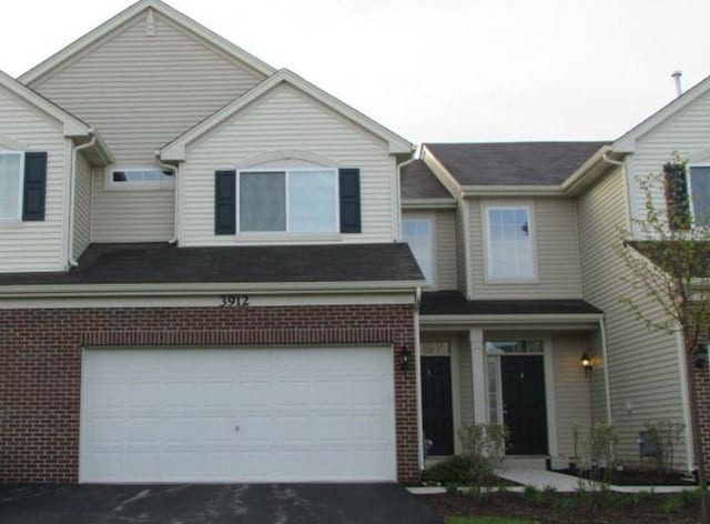 view of front of house featuring brick siding, an attached garage, and aphalt driveway