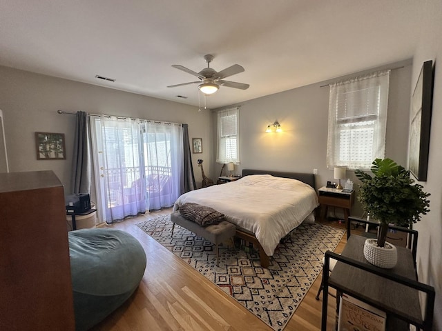 bedroom with visible vents, a ceiling fan, wood finished floors, and access to exterior