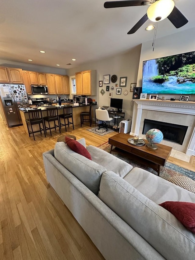 living room with recessed lighting, ceiling fan, light wood-style flooring, and a high end fireplace