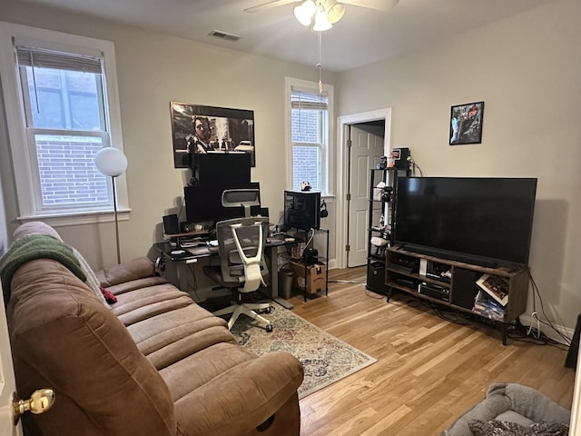 living area with a ceiling fan, wood finished floors, and visible vents
