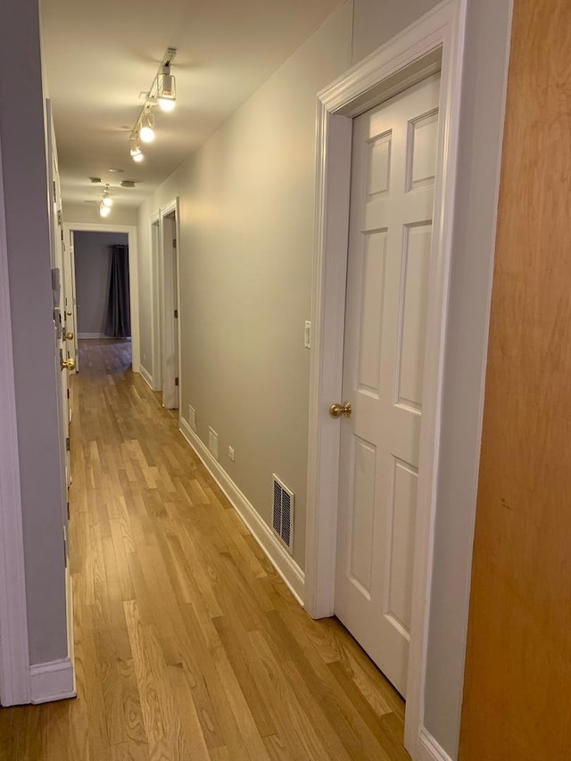 corridor featuring visible vents, light wood-style floors, and baseboards