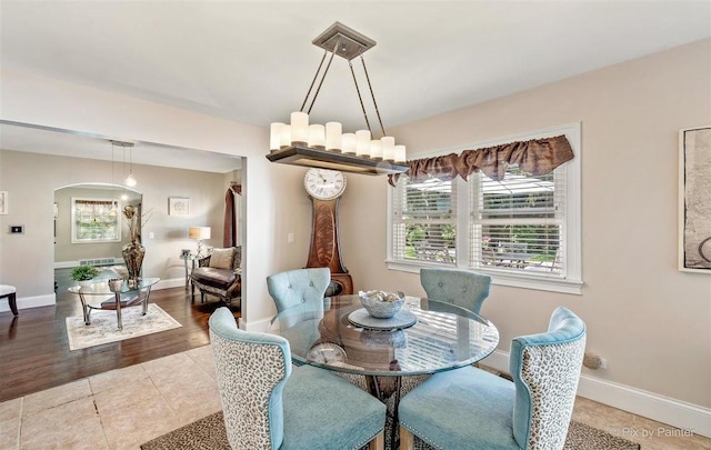 dining space with baseboards, arched walkways, and tile patterned floors