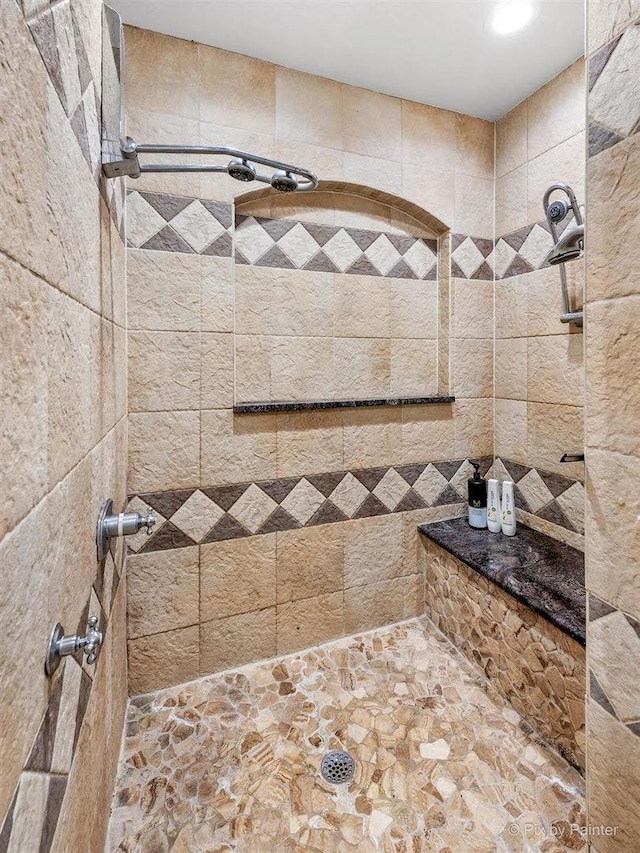 full bathroom with stone finish flooring and a tile shower