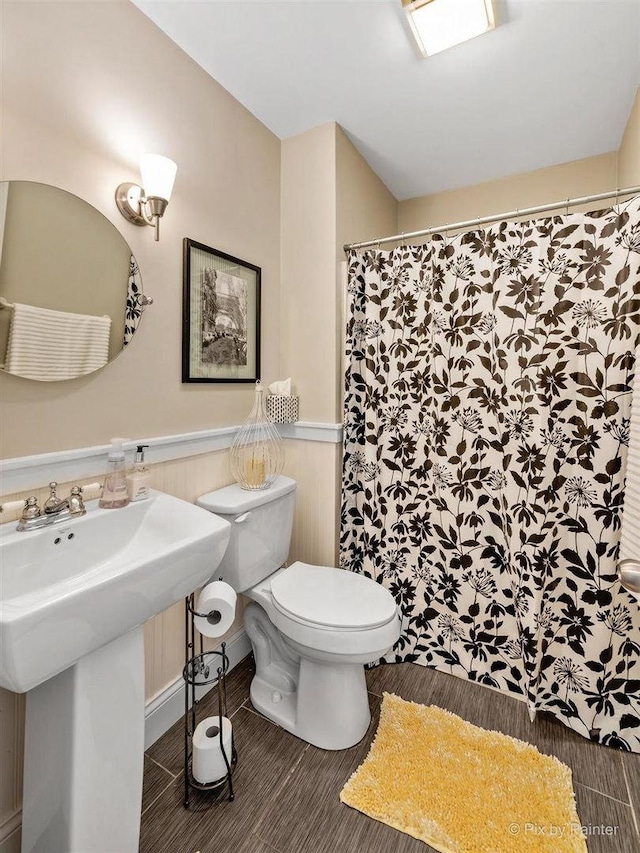 full bath featuring toilet, a sink, and a shower with shower curtain
