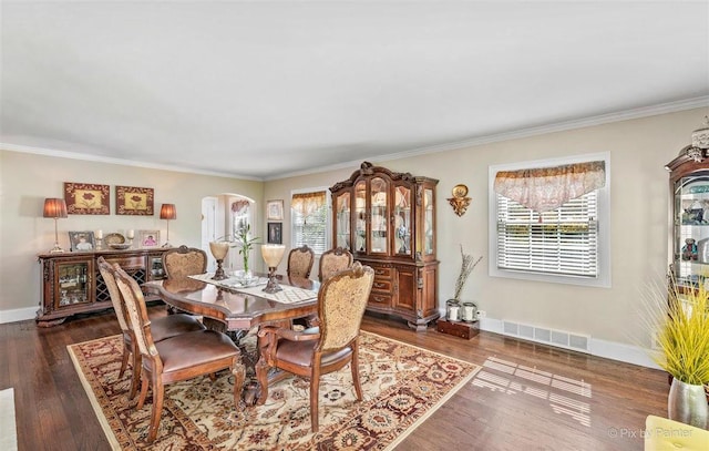 dining room featuring crown molding, arched walkways, visible vents, and wood finished floors