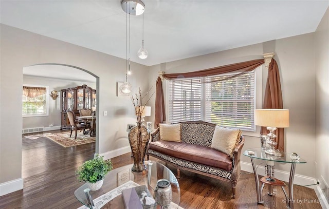 living area featuring baseboards, arched walkways, wood finished floors, and visible vents