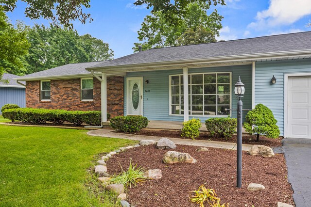 2409 Valkar Ln, Champaign, IL 61822 - single story home featuring a front lawn, a porch, brick siding, and a shingled roof