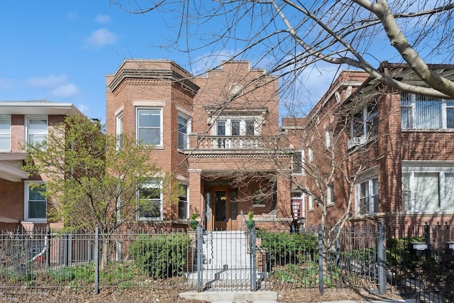 townhome / multi-family property with a balcony, a fenced front yard, a gate, and brick siding