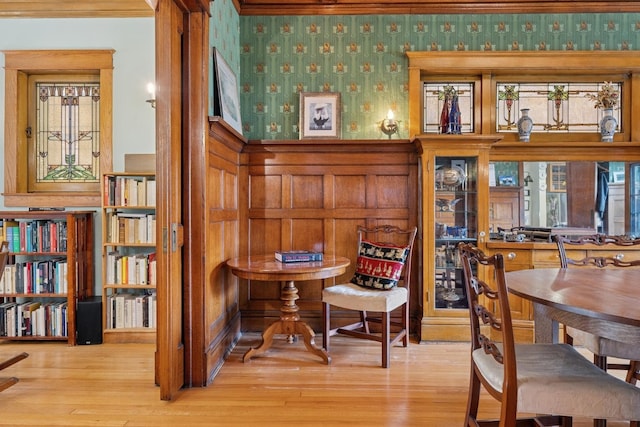 living area featuring wallpapered walls, a wainscoted wall, and wood finished floors