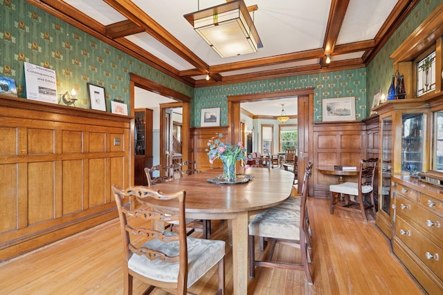 dining space with light wood-style floors, beamed ceiling, wallpapered walls, a wainscoted wall, and coffered ceiling