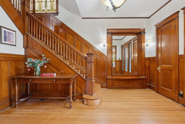 stairs with wainscoting, crown molding, and wood finished floors