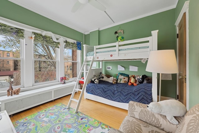 bedroom with a ceiling fan, radiator, wood finished floors, and ornamental molding