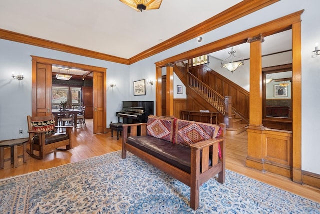 living room with crown molding, wood finished floors, wood walls, and stairs
