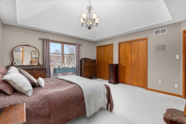 15306 S Heritage Dr, Plainfield, IL 60544 - bedroom with an inviting chandelier, visible vents, carpet flooring, multiple closets, and a raised ceiling