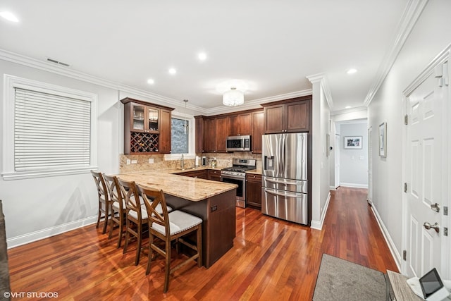 kitchen with a kitchen bar, a peninsula, a sink, stainless steel appliances, and baseboards