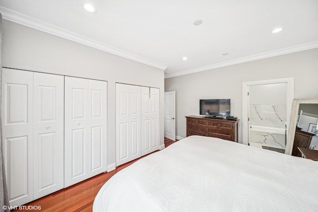 bedroom featuring two closets, ensuite bath, ornamental molding, recessed lighting, and wood finished floors