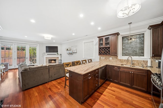 kitchen featuring a sink, appliances with stainless steel finishes, a peninsula, a kitchen bar, and dark brown cabinets