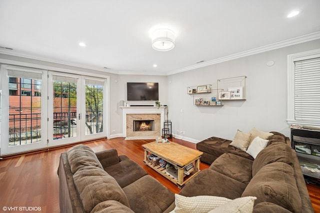 living room with baseboards, recessed lighting, crown molding, a premium fireplace, and wood finished floors