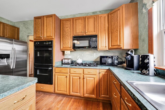 1581 Hunting Hound Ln, Bartlett, IL 60103 - kitchen with a sink, brown cabinetry, black appliances, and light wood finished floors