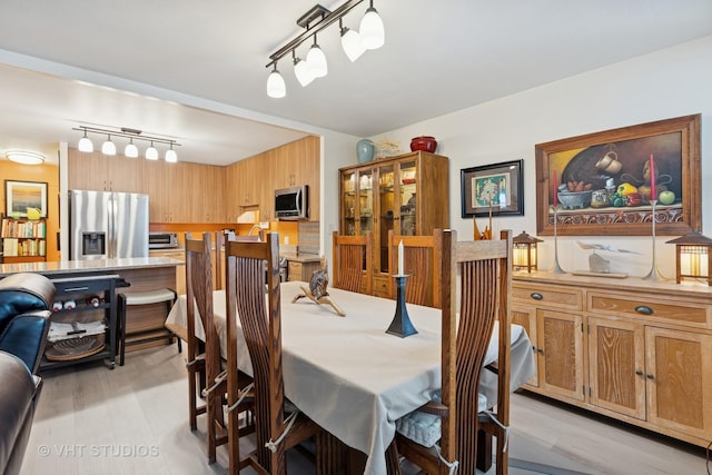 dining space with a toaster, rail lighting, and light wood-style floors