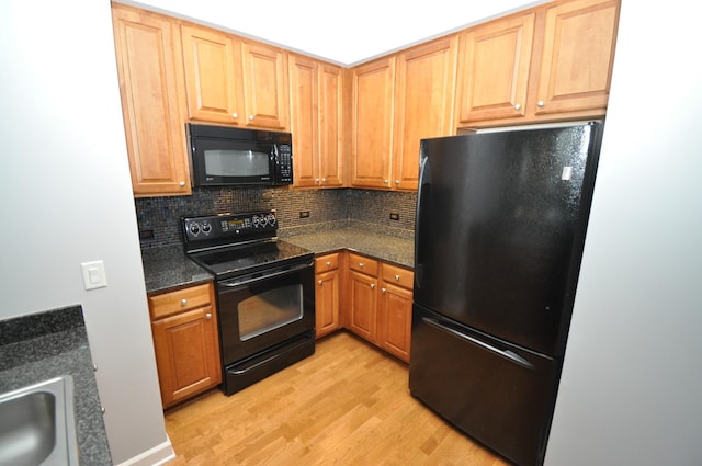 kitchen with light wood-type flooring, a sink, backsplash, and black appliances