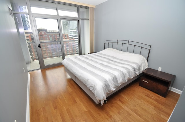 bedroom with wood finished floors, baseboards, and access to exterior