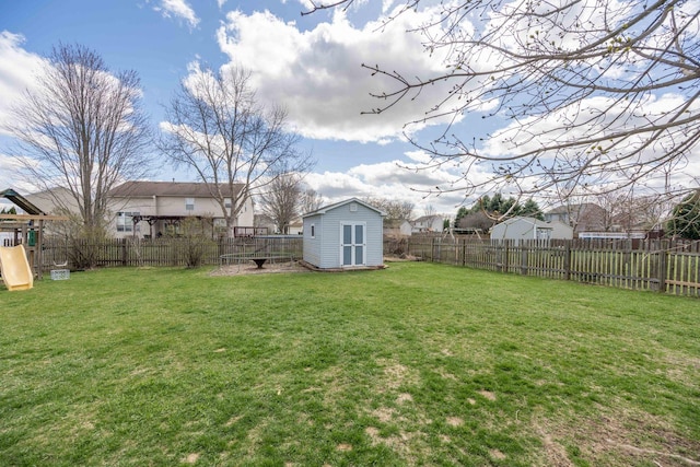 view of yard with a shed, a fenced backyard, a playground, and an outbuilding