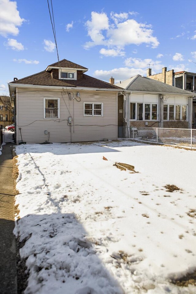 snow covered rear of property with fence