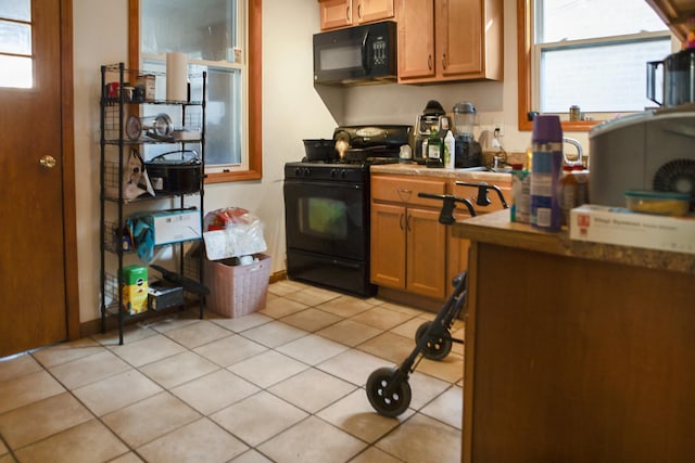 kitchen with light tile patterned floors, brown cabinets, and black appliances