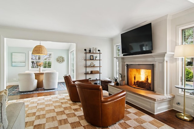 living room with a tiled fireplace, baseboards, ornamental molding, and wood finished floors