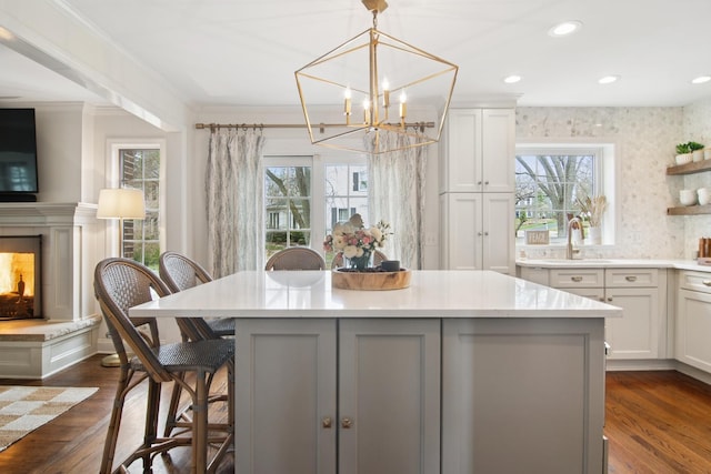 kitchen with light countertops, crown molding, a sink, and plenty of natural light